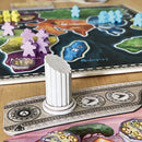 A close-up view of the board game 'First Empires' by Sand Castle. The image showcases a detailed game board featuring colorful regions representing different territories, with player pieces in purple, yellow, green, and blue. A white column piece stands on a scoring track, which includes icons and numbers for game progression.