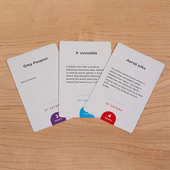 A close-up view of three game cards from the 'Monikers: More Monikers' game by Palm Court. The cards feature illustrated definitions of various terms: Grey Poupon, A vuvuzela, and Aerial silks, with corresponding point values. Each card is designed with distinct colored borders and text, enhancing the visual appeal and usability for gameplay.