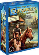 Carcassonne: Expansion 1 – Inns & Cathedrals box art showcasing the game title prominently. The design features medieval elements with characters, a horse, and scenic landscapes, hinting at the strategic gameplay. The Z-Man Games logo is visible at the bottom.
