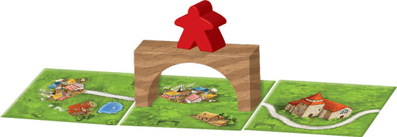 Carcassonne: Expansion 8 – Bridges, Castles and Bazaars game components, featuring a wooden bridge piece with a red meeple on top, surrounded by colorful terrain tiles depicting villages, a pond, and a castle.