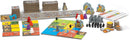 Queendomino board game by Blue Orange U.S.A. featuring colorful tiles and game pieces. The image shows the game board, various tiles, player pieces in different colors, coins, and score sheets, all arranged for gameplay, highlighting its vibrant design and strategic elements.