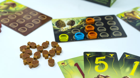 The Wonder Woods game features colorful components including acorn-shaped tokens, numbered cards, and a scoring board. The vibrant design encourages fun gameplay for families and friends, promoting strategic thinking and interaction.