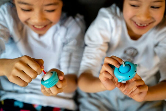 Two smiling children holding colorful Big Bubble Narwal keychains, one in turquoise and purple, while playing and engaging with the fidget toys, showcasing their joy and creativity.