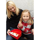 A mother and daughter enjoying a game of Double Shutter by Blue Orange U.S.A. The game is displayed in a vibrant red box, showing interactive pieces designed for family fun. The daughter, smiling and clapping her hands, is seated next to her mother, who is also engaged and smiling, highlighting the enjoyable experience of playing together. The background features a cozy setting, enhancing the family-oriented atmosphere.