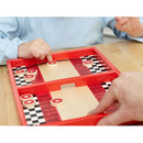 Two players engaged in a fast-paced game of Fastrack by Blue Orange U.S.A. The vibrant red game board features checkerboard patterns and star-marked pucks as they strategically aim to score points by sliding pucks into their opponent's area. A child’s hand is visible, focusing on the gameplay, while an adult hand assists in the game mechanics.