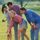 A group of four friends enjoying a game of bocce ball in a sunny park setting. They are smiling and engaged, with two individuals holding colorful bocce balls while preparing to play. The grassy area adds a vibrant outdoor feel to their recreational activity.