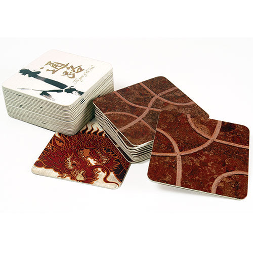 A set of Tsuro game tiles from Calliope, featuring beautiful designs including a dragon and intricate pattern. The tiles are stacked and displayed at an angle, showcasing their glossy finish and artistic illustrations. The game focuses on strategy and path creation.