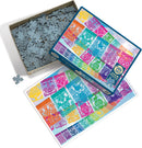The Cobble Hill Papier Picado jigsaw puzzle box featuring vibrant illustrations. The lid displays intricate designs in various colors, while the base shows numerous jigsaw pieces. A color illustration of the completed puzzle is laid beside the box, showcasing bright artwork inspired by traditional papel picado decorations. Perfect for puzzle enthusiasts and art lovers alike.