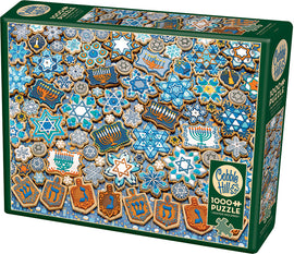 Cobble Hill Hanukkah Cookies jigsaw puzzle with 1000 pieces, featuring an array of beautifully decorated cookies shaped like stars, dreidels, and menorahs, in festive blue and gold colors. The puzzle box showcases an appealing design perfect for holiday-themed family activities.