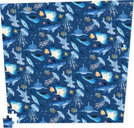 Crocodile Creek's Shark Reef: Almost Impossible Puzzle featuring a vibrant underwater scene filled with various sharks and jellyfish on a deep blue background. The 144-piece jigsaw puzzle showcases colorful marine life including starfish and corals, perfect for puzzle enthusiasts and ocean lovers alike.
