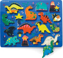 A colorful wooden jigsaw puzzle featuring a variety of dinosaurs and lush plants. The puzzle includes vibrant dinosaur shapes like T-Rex, Triceratops, and more, set against a blue background with artistic details such as flowers and a volcano.