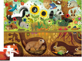 A colorful jigsaw puzzle featuring an illustrated scene of a backyard. The puzzle displays various animals such as a skunk, raccoon, rabbits, and a variety of plants and flowers, showcasing wildlife both above and below ground in a vibrant, cartoonish style.