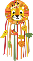 A vibrant DIY kit called Little Lion Dreamcatcher by DJECO, featuring a colorful lion face surrounded by various ribbons and leaves. The design incorporates bright colors like yellow, orange, and green, perfect for children's crafts.