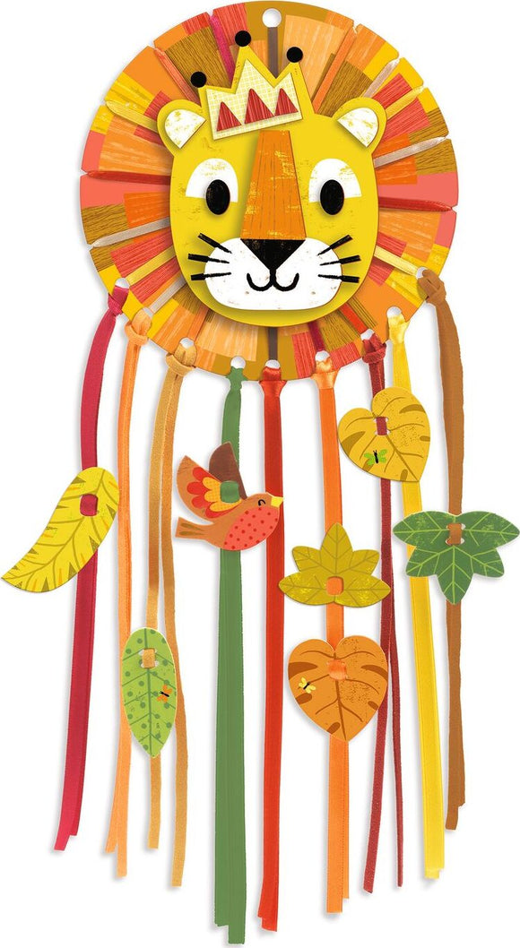 A vibrant DIY kit called Little Lion Dreamcatcher by DJECO, featuring a colorful lion face surrounded by various ribbons and leaves. The design incorporates bright colors like yellow, orange, and green, perfect for children's crafts.