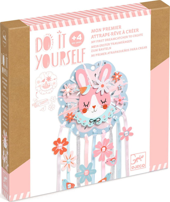 The 'Dreamer Dreamcatcher' DIY kit by DJECO features a colorful design with a cute bunny face, vibrant flowers, and attached ribbons. Ideal for children aged 4 and above to create their own decorative dreamcatcher.