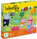 The Woolfy Family Game by DJECO features a colorful box design with a wolf and three pigs. The scene includes a cozy cabin, trees, and building bricks, illustrating a cooperative gameplay experience aimed at children aged 5 to 9. The game promotes teamwork and creativity in a playful setting.