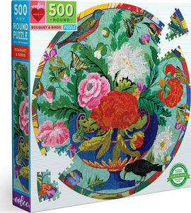 A vibrant 500-piece round jigsaw puzzle titled 'Bouquet & Birds' by Eeboo. The colorful design features a rich floral arrangement surrounded by butterflies and birds, set against a bright blue background. The box showcases the intricate artwork and includes a piece of the puzzle displayed next to it.
