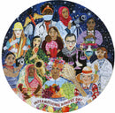 A 500-piece jigsaw puzzle titled 'International Women's Day' by Eeboo featuring a colorful illustration of diverse women from various professions and cultures. The image celebrates women’s achievements and empowerment, depicting figures such as a doctor, a lawyer, an artist, and others holding symbols of strength and creativity against a starry background.