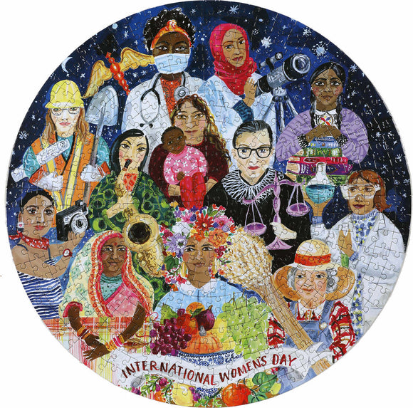 A 500-piece jigsaw puzzle titled 'International Women's Day' by Eeboo featuring a colorful illustration of diverse women from various professions and cultures. The image celebrates women’s achievements and empowerment, depicting figures such as a doctor, a lawyer, an artist, and others holding symbols of strength and creativity against a starry background.