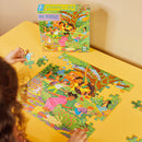 A child assembling the colorful Out to Play jigsaw puzzle by Eeboo, featuring a vibrant outdoor scene with children playing, surrounded by flowers and greenery. The puzzle box is visible in the background, showcasing the cheerful artwork.