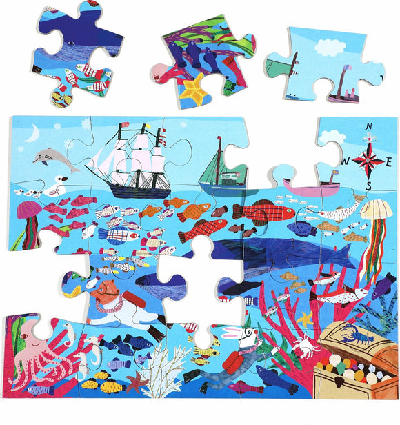 A colorful jigsaw puzzle featuring a vibrant underwater scene with various fish, jellyfish, and sea creatures. There is a depiction of a ship sailing on the waves, surrounded by coral reefs and treasure chests. Several jigsaw pieces are shown, with some already placed in the puzzle, displaying intricate illustrations of marine life.