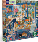 Eeboo's Blue Kitchen jigsaw puzzle featuring a vibrant kitchen scene. The puzzle depicts a cozy kitchen with a blue color scheme, filled with various cookware, fruits, and two sleeping dogs on a colorful rug. The intricate details showcase baskets of vegetables, cookbooks, and hanging utensils, making it a delightful and engaging puzzle for all ages.