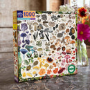 The Mushroom Rainbow jigsaw puzzle by Eeboo features a colorful assortment of 1000 different mushroom illustrations, showcasing various shapes, sizes, and colors. The puzzle box design includes detailed images of fungi along with text labels, set against a neutral background. The packaging highlights that it is made from recycled materials, making it an eco-friendly choice for puzzle enthusiasts.