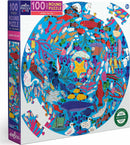 Eeboo Under the Sea Round Puzzle featuring colorful marine life in a vibrant underwater scene. The jigsaw puzzle displays a variety of fish, sea creatures, and whimsical patterns, ideal for children aged 5 and up. The box showcases a round puzzle with 100 pieces and a diameter of 20 inches, made from recycled materials.