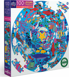 Eeboo Under the Sea Round Puzzle featuring colorful marine life in a vibrant underwater scene. The jigsaw puzzle displays a variety of fish, sea creatures, and whimsical patterns, ideal for children aged 5 and up. The box showcases a round puzzle with 100 pieces and a diameter of 20 inches, made from recycled materials.