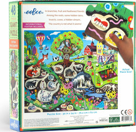 Eeboo Within the Country 48-piece giant jigsaw puzzle featuring a colorful illustration of rural scenes with various animals and nature elements. A hand is shown placing a puzzle piece. Includes an informational poster. The puzzle measures 30 x 24 inches, perfect for family fun and educational play.