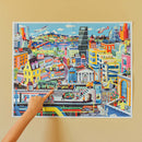 A colorful jigsaw puzzle of a bustling city scene featuring skyscrapers, parks, and various transport including cars and boats. People are seen engaging in different activities, with shops and cafes depicted in a vibrant, cartoonish style. The artwork captures urban life with a helicopter flying above and a train passing below.