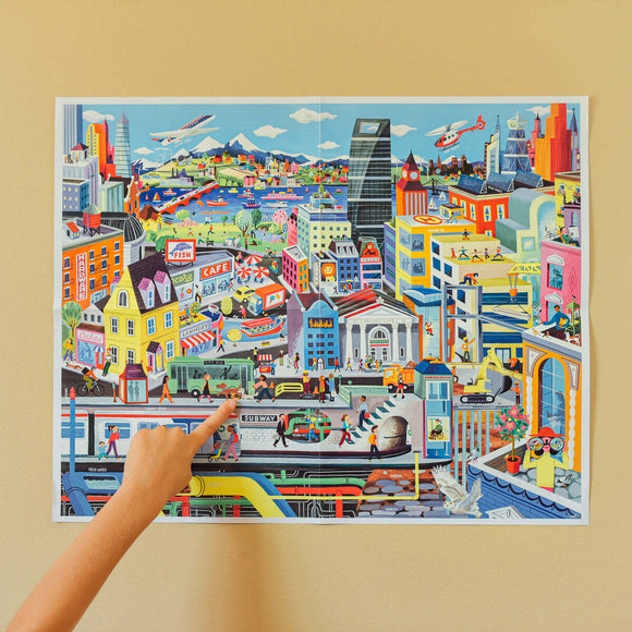 A colorful jigsaw puzzle of a bustling city scene featuring skyscrapers, parks, and various transport including cars and boats. People are seen engaging in different activities, with shops and cafes depicted in a vibrant, cartoonish style. The artwork captures urban life with a helicopter flying above and a train passing below.
