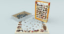 Eurographics Chocolate jigsaw puzzle featuring an assortment of delectable chocolate desserts. The puzzle box is displayed alongside partially completed puzzle pieces spread across a light surface. The puzzle has 1000 pieces and includes various sweet treats like cupcakes, pralines, and brownies, perfect for puzzle enthusiasts and chocolate lovers alike.