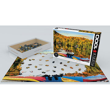 A visually captivating jigsaw puzzle featuring a serene lakeside cottage scene in Quebec. The puzzle pieces are spread out on a table, with the colorful box prominently displayed next to it. The image showcases autumn foliage, clear blue waters, and a rustic boat, inviting puzzle enthusiasts to immerse themselves in a peaceful, natural setting.