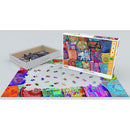 The Indian Pillows jigsaw puzzle by Eurographics features a vibrant and colorful design showcasing a variety of decorative pillows. The image displays the puzzle box alongside the partially completed puzzle laid out on a table, with pieces scattered around. This 1000-piece puzzle offers a delightful challenge for puzzle enthusiasts and a beautiful visual experience.