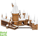A detailed metal model of Hogwarts Castle covered in snow, featuring intricate towers, spires, and architectural details. The castle is depicted in a warm bronze color against a white background, showcasing its enchanting winter charm.