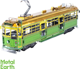 A detailed model of the Melbourne W-Class tram made from metal by Fascinations. It features a vibrant green and gold color scheme and intricate detailing, showcasing its realistic design. The tram is positioned at an angle, highlighting its showcase of craftsmanship with visible windows, wheels, and overhead power lines.