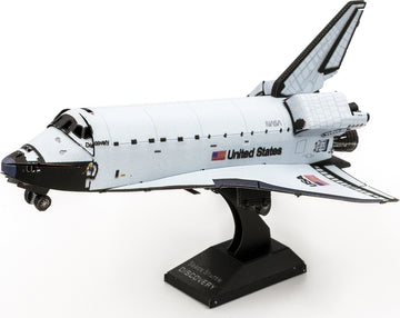 Metal Earth DIY kit of the Space Shuttle Discovery, featuring detailed metal construction pieces that assemble into a realistic model. The model showcases intricate designs that represent the iconic NASA spacecraft, complete with labels and textures, set on a sturdy black stand.
