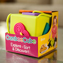 The OombeeCube by Fat Brain Toys is a vibrant, colorful sorting and discovery game designed for children aged 6 months and older. The cube features soft, textured shapes in various colors including pink, purple, and green, making it visually engaging. Its sturdy design is perfect for little hands, promoting sensory exploration and fine motor skills. The packaging showcases a young child happily engaging with the toy, emphasizing its playfulness and educational value.