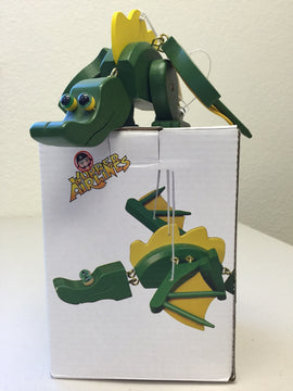 Wupper-Dragon Green by Wupper Airlines, a whimsical green dragon figure with yellow accents. The dragon is crafted from wood, featuring googly eyes and movable parts for playful interaction. It is displayed on a white box that showcases its design.