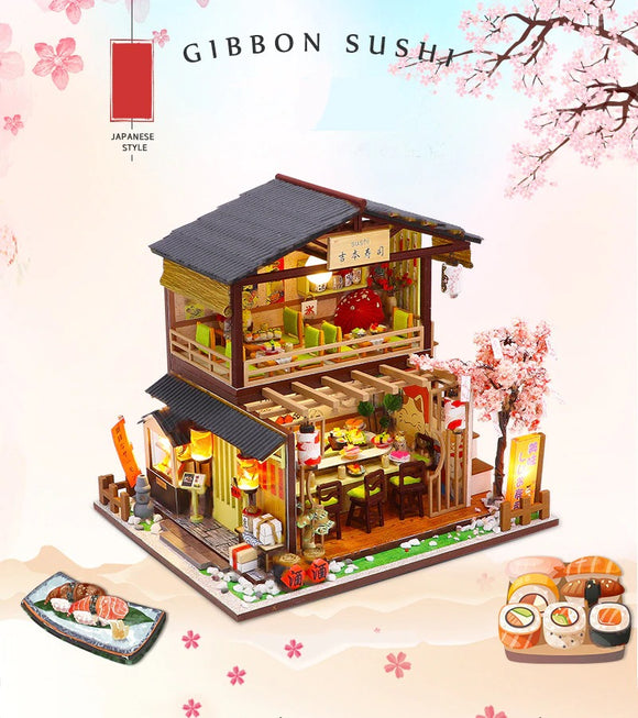 A beautifully detailed DIY kit called Gibbon Sushi showcasing a miniature sushi restaurant. The two-story design features a vibrant interior with a dining area filled with sushi dishes and decor, complemented by a sushi platter in the foreground. Delicate cherry blossom accents enhance the Japanese style of the kit. Ideal for craft enthusiasts and fans of Japanese culture.