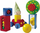 Colorful wooden toy blocks from HABA, featuring a smiling character wearing a striped hat, a car, and various shaped blocks with balls. The vibrant colors and playful design encourage imaginative play and fine motor skills development for young children.