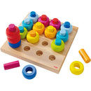 Colorful Pegging Game from Haba, featuring a wooden board with multiple holes and vibrant pegs in various shapes and colors. Ideal for developing fine motor skills and color recognition in young children.