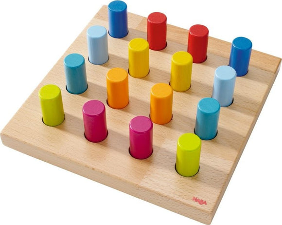 Pegging Game Rainbow Whirls by Haba featuring a wooden board with 16 colorful pegs in vibrant shades of red, orange, yellow, green, blue, and pink. The pegs are arranged in a grid pattern, promoting hands-on learning and fine motor skills. Ideal for children, this game encourages creativity and problem-solving.