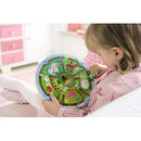 A young child plays with the Magnetic Game Number Maze by HABA, positioned on their lap. The colorful game features a round board with pathways, numbers, and animal illustrations. The child uses a magnetic wand to guide pieces through the maze, enhancing their fine motor skills and number recognition.