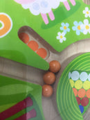 Close-up view of the Magnetic Game Number Maze by HABA. The image shows colorful wooden paths with small orange balls situated within the maze structure, surrounded by vibrant green and playful designs, including flowers and a sheep.