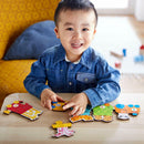 A young child smiles while playing with the HABA Number Train jigsaw puzzle on a wooden table. The puzzle features colorful pieces representing numbers and playful characters, encouraging early learning and fine motor skills.