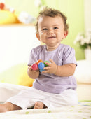 A cheerful baby sitting on a soft surface, playing with colorful clutching toys. The baby has a joyful expression and is holding vibrant plastic balls in various colors, promoting sensory play and motor skill development.