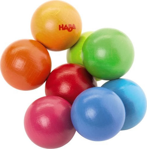 A colorful collection of eight wooden balls arranged playfully. The balls are in vibrant colors: orange, red, pink, green, blue, and yellow, with the Haba logo visible on one of the balls. These balls are smooth and designed for tactile play and engagement.
