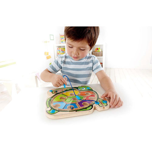 A young child playing with the Colorback Sea Turtle from HaPe International, engaging with a colorful, wooden puzzle featuring numbers and a turtle design. The child uses a wand to manipulate pieces on the turtle's back, promoting fine motor skills and cognitive development in a bright, playful environment.